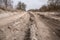 Bad country road. A dirt road damaged by the wheels of a heavy truck. Clay, dirt. Concept: problem with the roads; human impact on