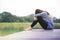 Bad Day Concept. Sadness Woman Sitting by the River on Wooden Patio Deck