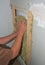 Bad example of indoor house fiberglass insulation without glowes. Worker hands insulating house drywall with rock wool