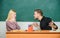 Bad news for her. Frustrated teacher and schoolmaster sitting at desk. Handsome man and cute woman back to school