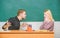 Bad news for her. Frustrated teacher and schoolmaster sitting at desk. Handsome man and cute woman back to school