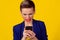 Bad news. Portrait angry mad remorseful young woman looking at mobile phone isolated on yellow background wall. Negative human