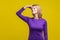 Bad smell. Portrait of young woman in purple dress pinching her nose. isolated on yellow background