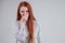 Bad smell unhappy redhead business woman in a striped shirt holding her nose indoor studio shot white background.