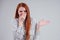 Bad smell unhappy redhead business woman in a striped shirt holding her nose indoor studio shot white background.