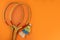 Badminton rackets and shuttlecocks on a bright orange background