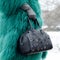 Bag close-up in female hands. Stylish modern and feminine image, style. Girl in a green coat with a black bag and gloves