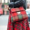 Bag closeup in female hands. Bright image, style. Girl in a red plaid skirt