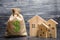 A bag with money and three houses. Concept of real estate acquisition and investment. Affordable cheap loan, mortgage. Taxes