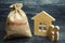 A bag with money and the word Mortgage and a wooden house. The accumulation of money to pay interest rates on mortgages. Buying a
