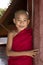 Bagan, Myanmar, December 29, 2017: Young Buddhist novice looks mischievously behind a red pillar