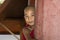 Bagan, Myanmar, December 29, 2017: Young Buddhist novice looks mischievously behind a red pillar