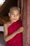 Bagan, Myanmar, December 29, 2017: Young Buddhist novice looks mischievously behind a red pillar in a pagoda in Bagan