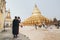 Bagan, Myanmar - March 2019: Buddhist monk taking picture of Shwezigon Paya golden temple