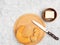 Bagel on cutting board, butter, knife on white concrete background