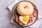 Bagel with heart-shaped boiled egg, tomato, cheese and herbs on a plate. Top view. Closeup