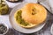 Bagel with pistachio cream butter and a jar of butter on a plate on the table