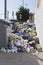 Bags full of trash surrounding dumpsters, vertical