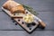 Baguette on a cutting board, butter and blueberries on a wooden table. Top view