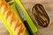 Baguette, knife on cutting board, jar with canned sprats on wooden table. Top view