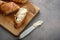 Baguette loaves and slices with knife and butter.