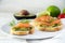 Baguette sandwiches with smoked salmon and avocado cream or guacamole as healthy party canapes on a white plate, ingredients in t