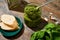 Baguette slices, pesto sauce in jar, grater and fresh ingredients on stone surface