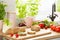 Baguette, tomatoes, pink mug, celery and herbs on a countertop in a kitchen interior. Real photo