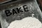 Bake Word Written on Baking Sheet Covered with White Flour