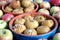 Baked apples in round clay dishware and lot lot of ripe fresh apples on blue tablecloth around