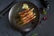 baked aspargus covered with bacon on a black ceramic plate