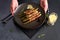 baked aspargus covered with bacon on a black ceramic plate