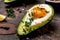 Baked avocado with eggs on wooden background. Healthy breakfast. Avocado stuffed with eggs. Food recipe background. Close up