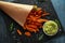 Baked butternut squash fries with sea salt, rosemary in paper cone. Pumpkin chips and quacamole dip