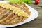 Baked capelin on a white plate on a wooden table.