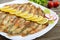 Baked capelin on a white plate on a wooden table.