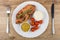 Baked carbonade, tomatoes, mustard, mayonnaise in plate, fork an