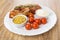 Baked carbonade, tomatoes, mustard, mayonnaise in white plate