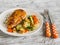 Baked chicken breast with brussels sprouts, onions and carrots on a white plate on wooden surface.