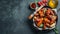 Baked chicken wings in barbecue sauce with sesame seeds and parsley in a cast iron pan on a dark concrete table. Top view with