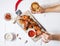 Baked chicken wings with sauce on white wood background. Woman hands hold glass of beer