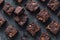 Baked chocolate brownie squares on mottled grey background texture - selective focus