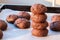 Baked cracked round chocolate cookies piled up on top of each other on a baking sheet with parchment paper