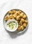 Baked crispy parmesan bread crumbs cauliflower bites with yogurt sauce on lightl background, top view