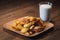 Baked crispy potatoes in a brown plate and milk in a cut glass