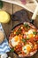 Baked eggs with chorizo, potatoes and tomatoes in a pan on the table. top view