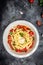 Baked feta pasta with cherry tomatoes, olive oil and herbs in a pan. Trend mixing macaroni and cheese. Food recipe vertical image