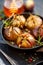 Baked figs stuffed with gorgonzola cheese, pine nuts, honey and herbs in a black dish on a dark, stone background, top view.