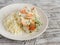 Baked fish with lemon and herbs and cous cous on a white plate, on bright wooden surface