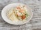 Baked fish with lemon and herbs and cous cous on a white plate, on bright wooden surface.